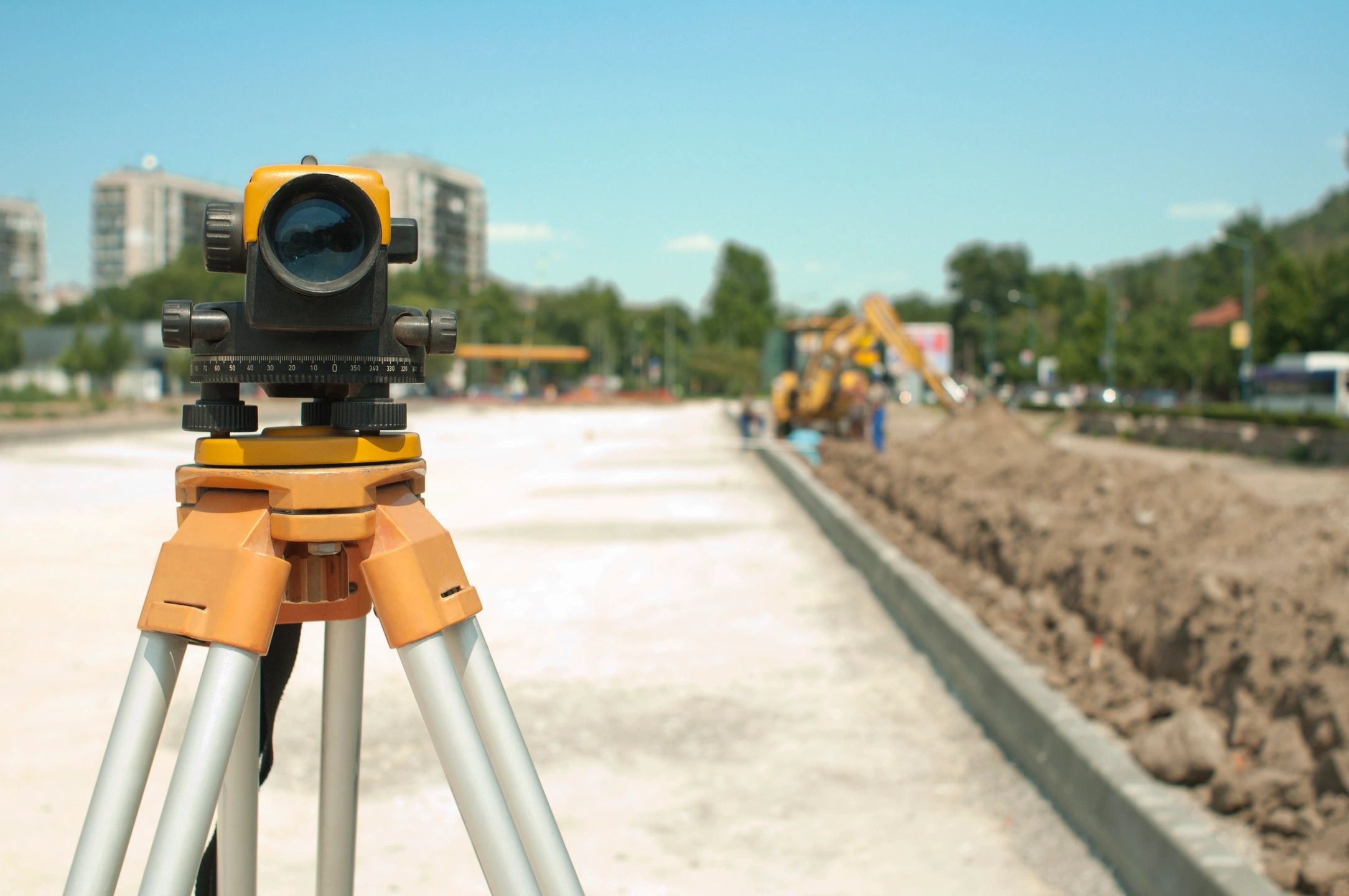 A yellow and black surveying instrument on the side of road.